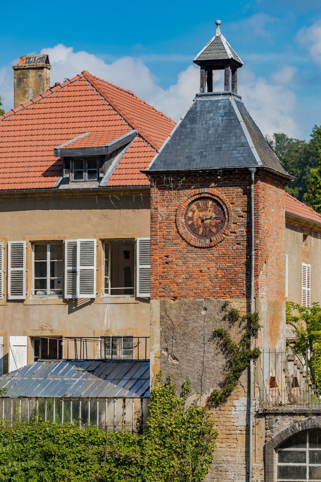 Tour de l'horloge en briques devant une partie des bâtiments des Forges de Buré d'Orval.